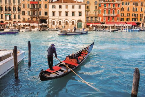 A gondolier manoeuvrings a gondola in the canals of Venice 