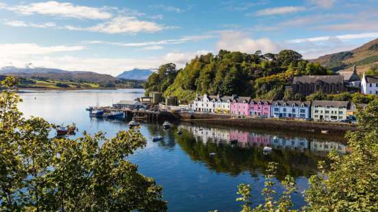 Look out to the harbour of Portree with colourful buildings along the shore of the picturesque fishing village