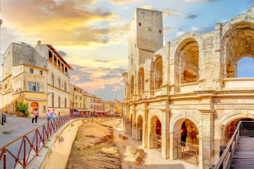 An old limestone building with tourists visiting in the old town of Arles in France 
