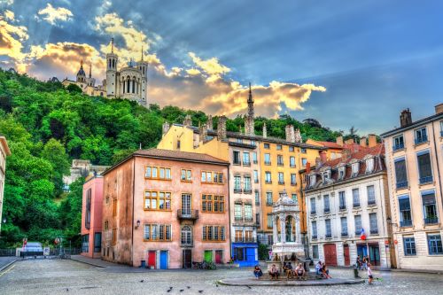 Coloured buildings with a water fountain in the foreground and a castle on top of a hill in the background 