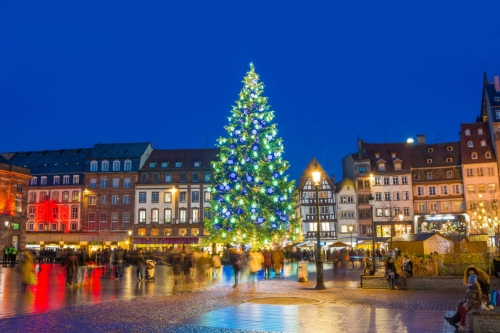 A lit-up Christmas tree in the middle of a Christmas market in a European town