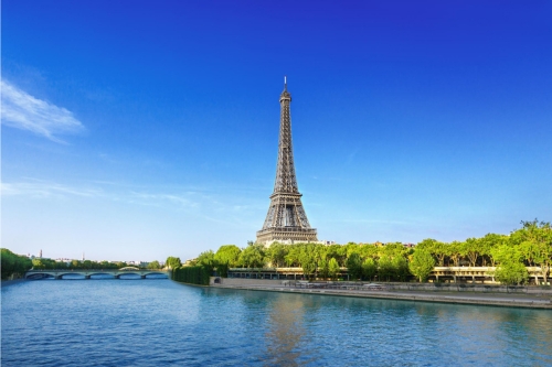 The river Seine passing the Eifel tower against a bright blue sky