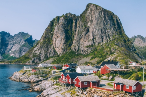 Typical Scandinavian houses built at the shore with steep mountains in the backgrounds 