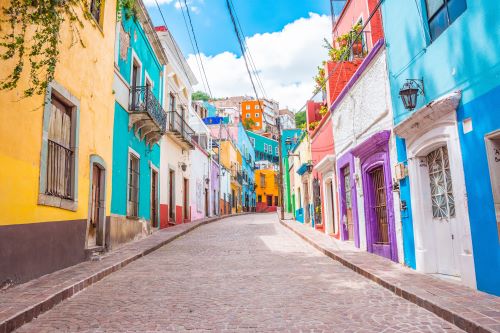 A cobblestone street with bright colourful buildings on either side and old style balconys