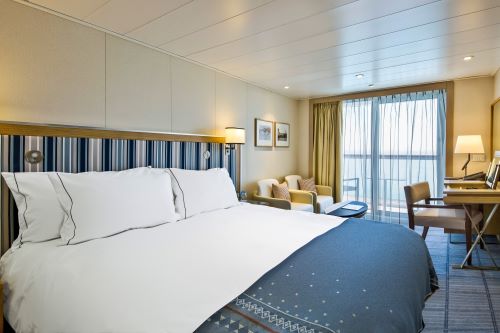 A veranda stateroom onboard a cruise ship with blue and light brown decor 