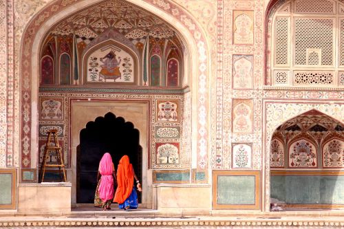 Two women entering Amber Fort with its majestic and intricate carvings