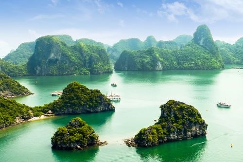 Aerial view of Halong Bay scattered with rocky and earthen islands in the form of jagged limestone pillars jutting out from the sea