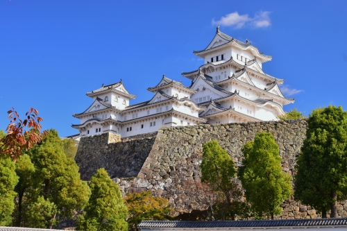 The grand, white, multi-tiered Japanese fortress with Himeji Castle towards a blue sky