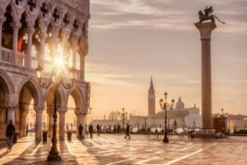 The sun sitting low at St Marks Square in Venice throwing long shadows of the building on the ground