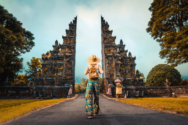 A woman with a backpack walking through Handara Gate in Bali, Indonesia