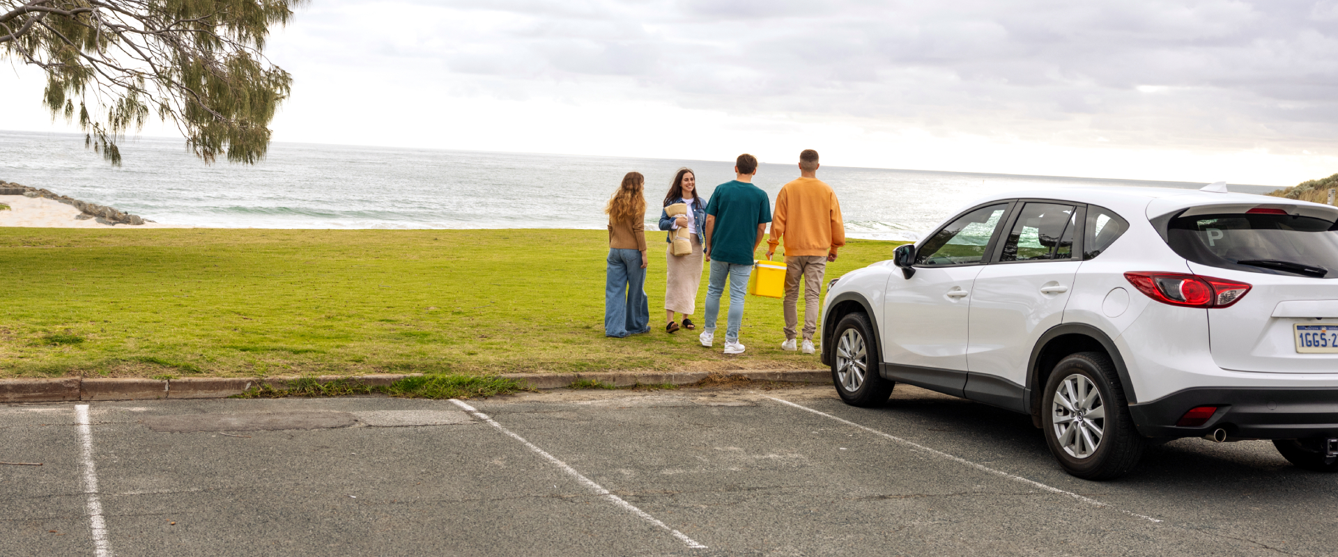 Four young people walking towards the beach from their car