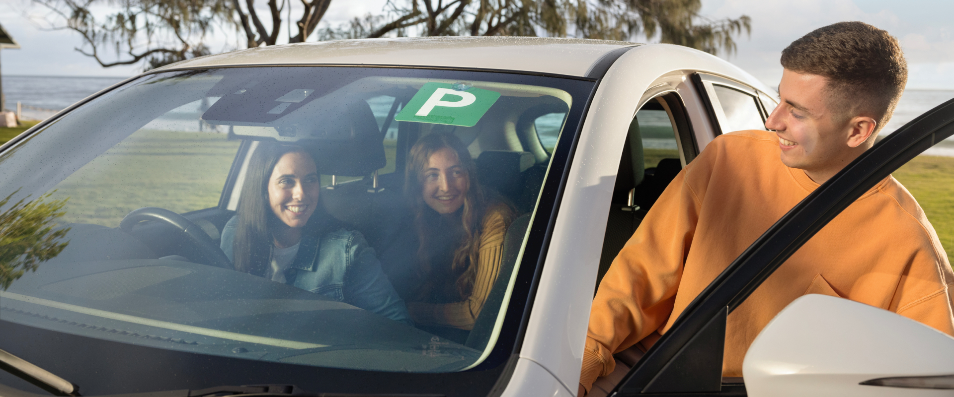 Young male getting into car with friends