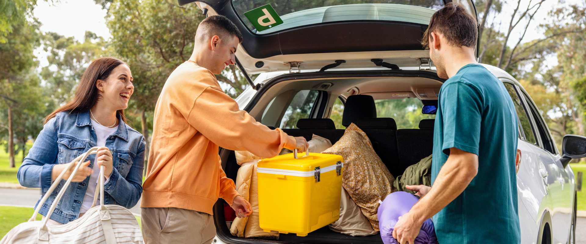 Three people packing the boot of a car for a picnic