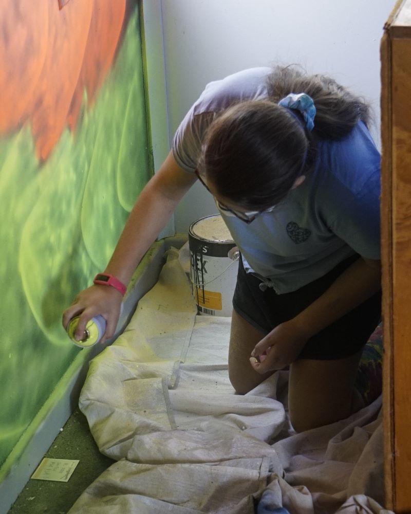 Local youth have a go at street art as they help create the Hub's vibrant mural