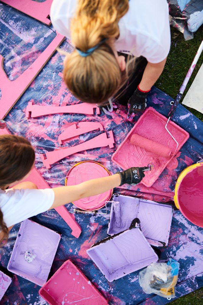 Young people paint outdoor furniture.